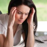 Image of a woman sitting at a desk with her head in her hands