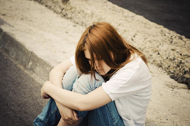 Picture of a teenage girl sitting hugging her knees