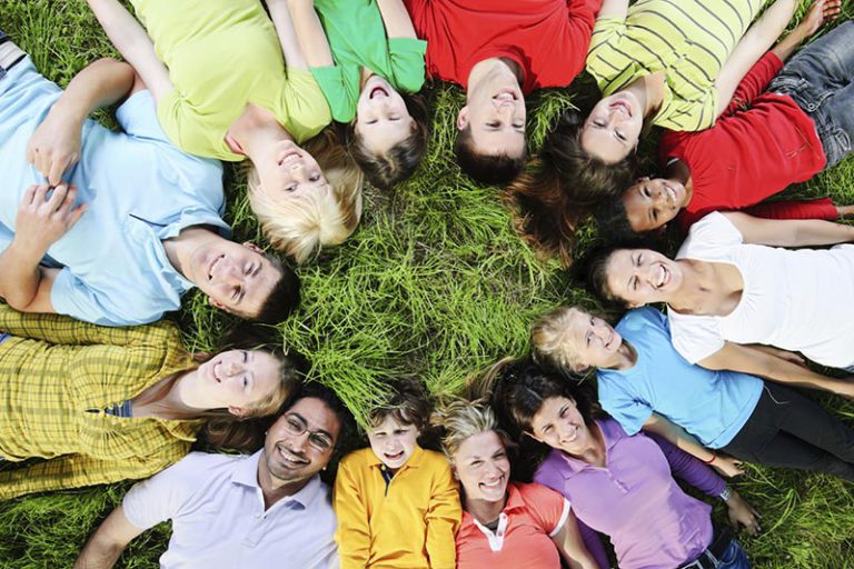 Picture of a group of adults and children lying in a circle on the grass